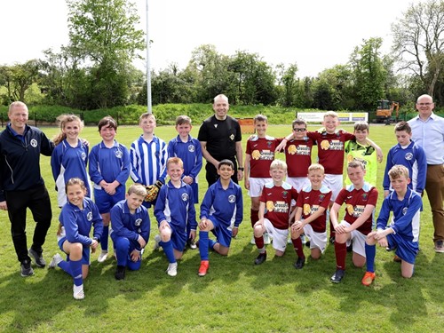 Secretary of State Chris Heaton-Harris at Crewe Park with the football teams from Rowandale Integrated Primary School and Crumlin Integrated Primary School, whose match he refereed.jpg